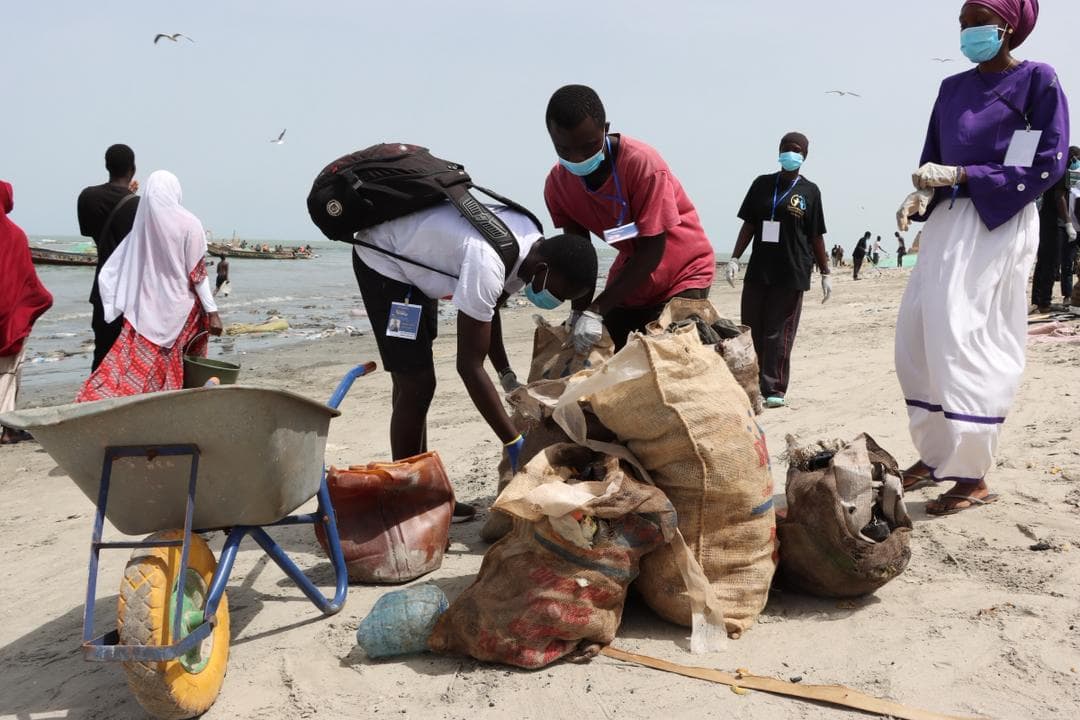 SMF volunteers working together at a community wheelbarrow cleanup in The Gambia